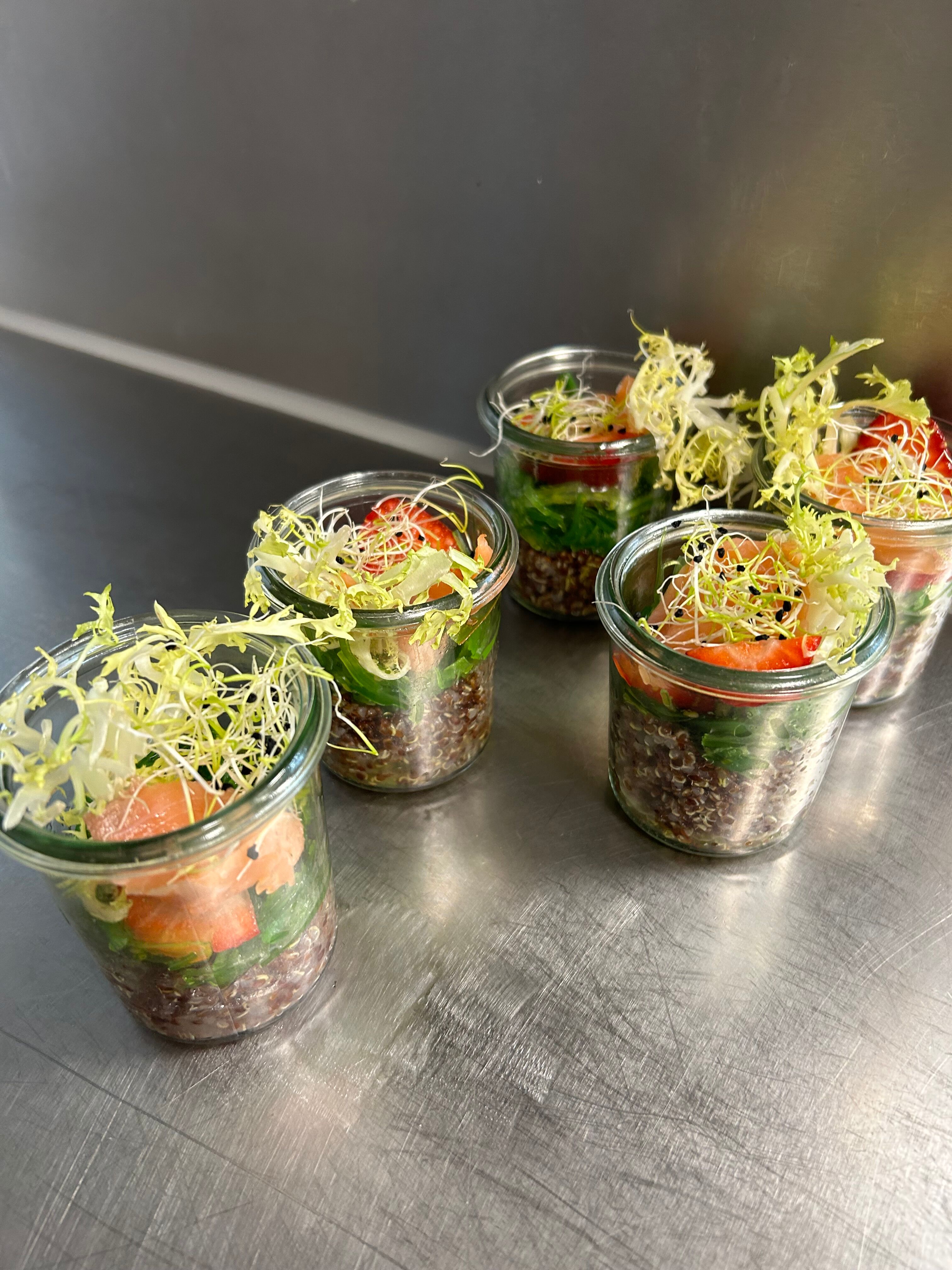 Schichtsalate im Glas mit Linsen, Gemüse und Sprossen auf Edelstahltisch