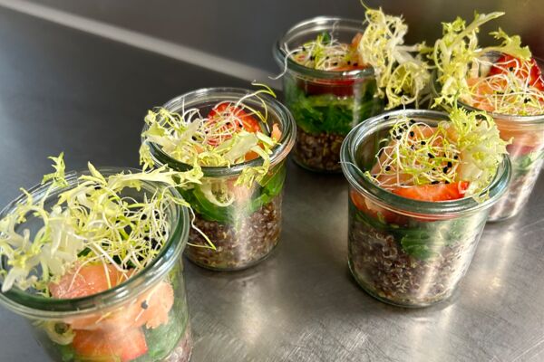 Schichtsalate im Glas mit Linsen, Gemüse und Sprossen auf Edelstahltisch