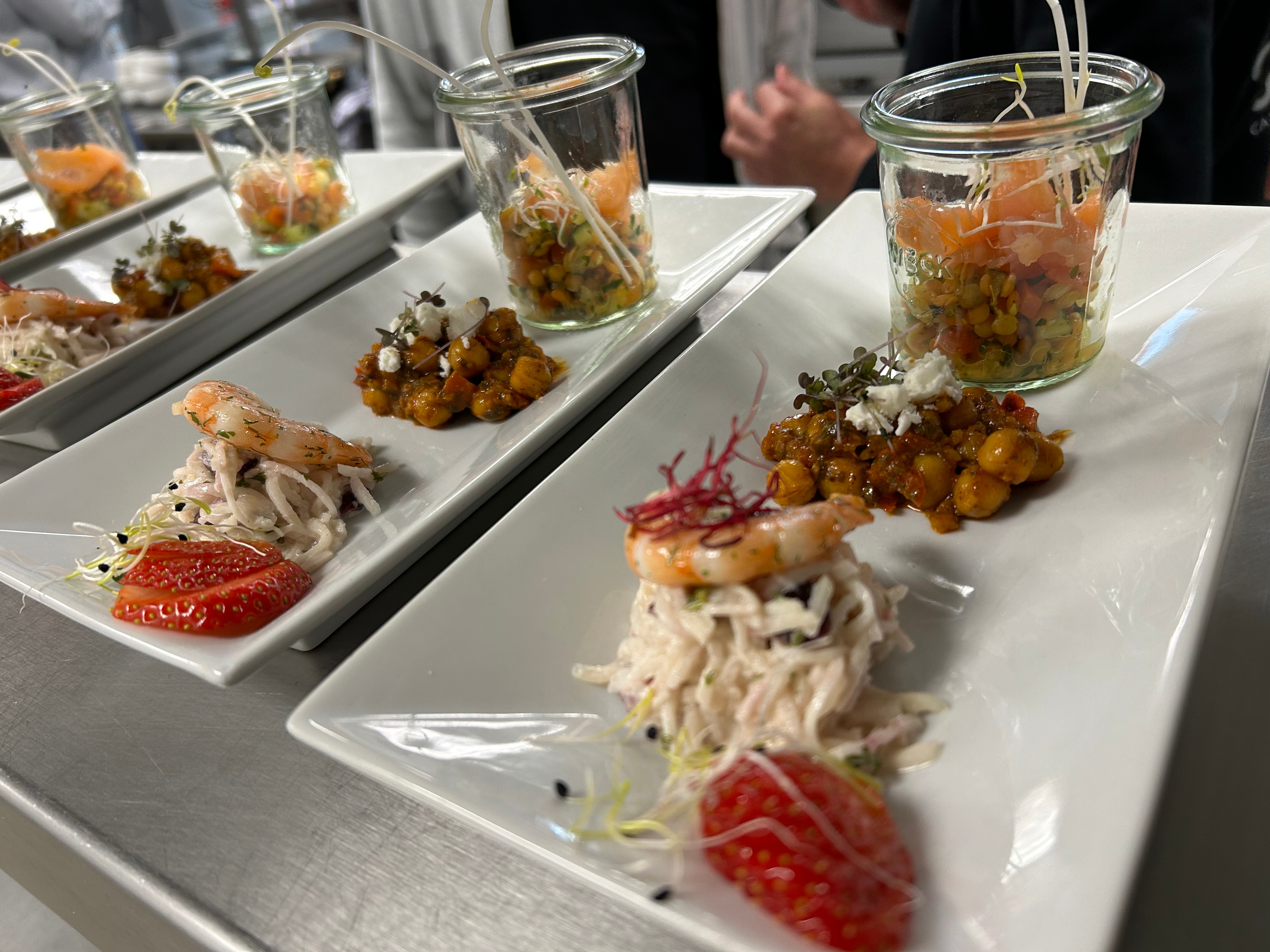 Fingerfood-Teller mit Garnele, Kichererbsen und Lachstatar im Glas beim Flying Buffet Worksho