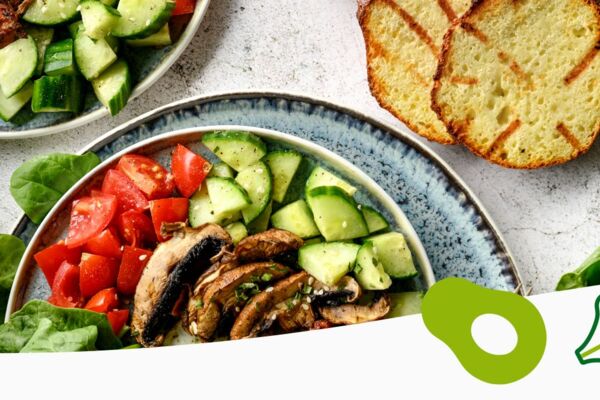 Zwei bunte Bowls mit frischem Gemüse, Champignons und gegrilltem Brot