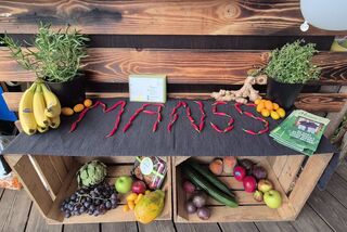 Obst- und Gemüsestand von Manss Foodservice mit frischen Früchten, Kräutern und dem Schriftzug ‚MANSS‘ aus Chilischoten.