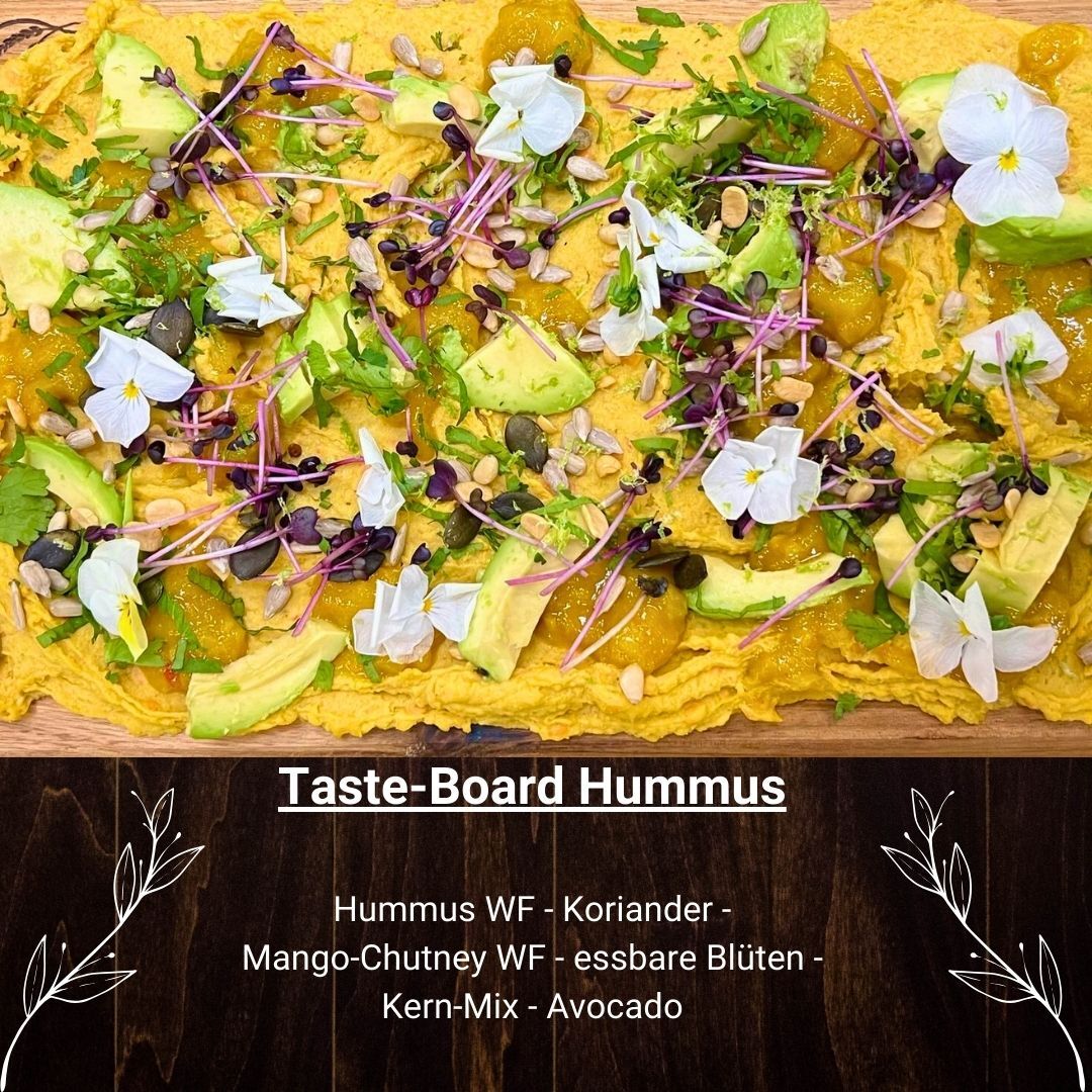 Kreativ angerichtetes Taste-Board mit Hummus, Mango-Chutney, Avocado, essbaren Blüten, Kernen und frischen Kräutern