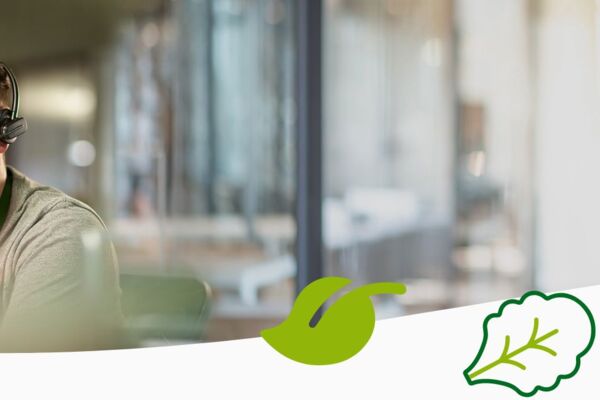 Freundlicher Mitarbeiter mit Headset an einem Schreibtisch, im Hintergrund ein modernes Büro, ergänzt durch grüne grafische Icons.