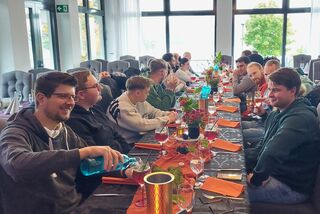 Mitarbeitergruppe beim festlich gedeckten Mittagessen nach einer herbstlichen Waldpilz-Exkursion, mit herbstlicher Dekoration und fröhlicher Atmosphäre.