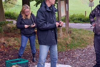 Jochen Beier erklärt während einer Waldpilz-Exkursion verschiedene Pilzarten, umgeben von Teilnehmern im herbstlichen Wald.