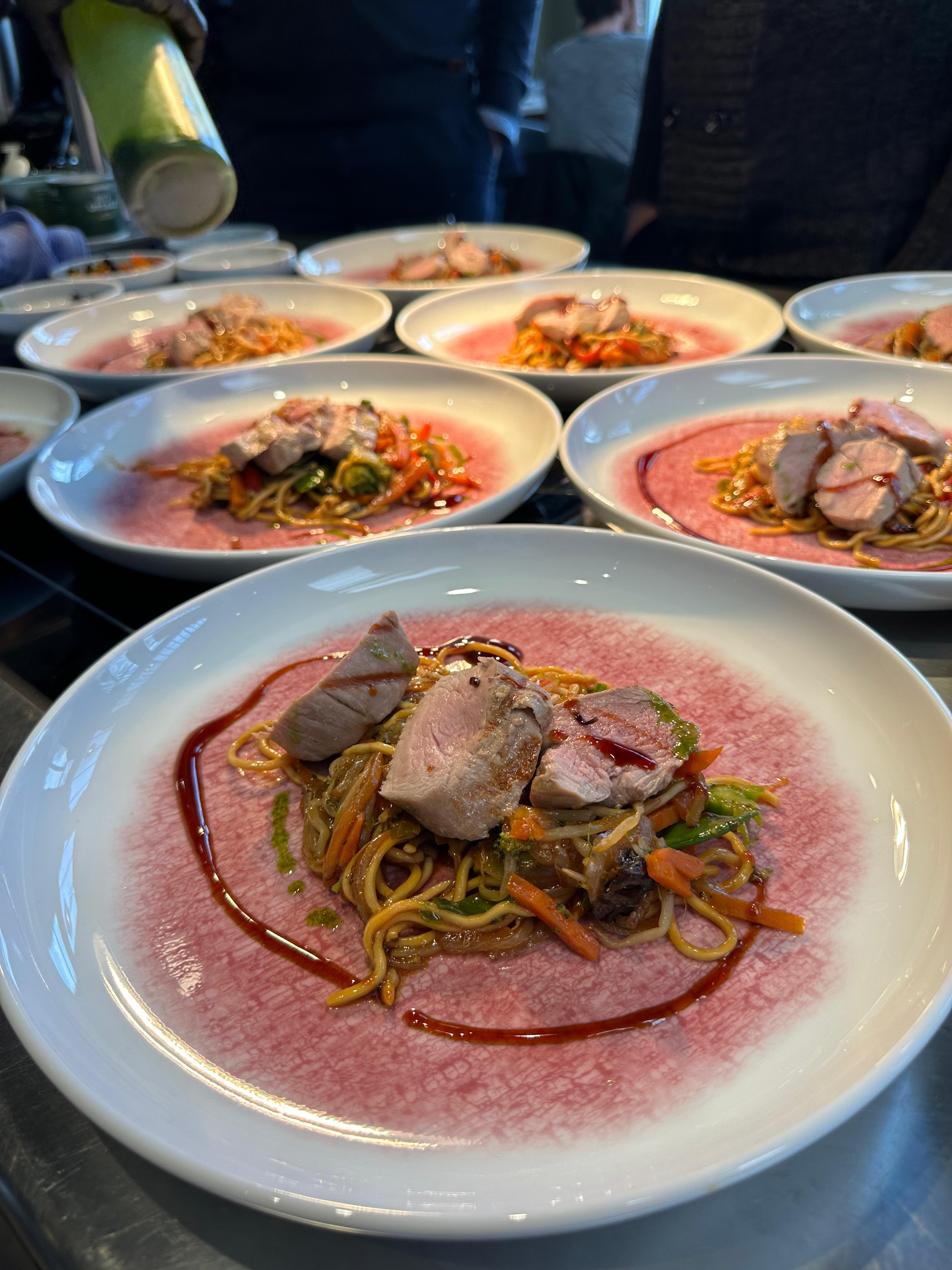 Angerichtete Teller mit Schweinefilet auf Mie-Nudeln und Asia-Gemüse, garniert mit Teriyaki-Soße – Hauptgang beim Frühlingsküche-Workshop von Manss Foodservice