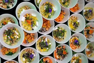 Viele bunte Bowls mit Reis, Gemüse, Tofu und essbaren Blüten – frisch zubereitet für das Jubiläum des ATLANTIC Hotels Münster.
