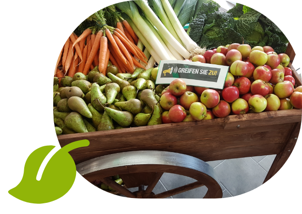 Holzwagen mit frischem Obst und Gemüse wie Äpfeln, Birnen, Karotten und Lauch – Regionalität sichtbar gemacht.
